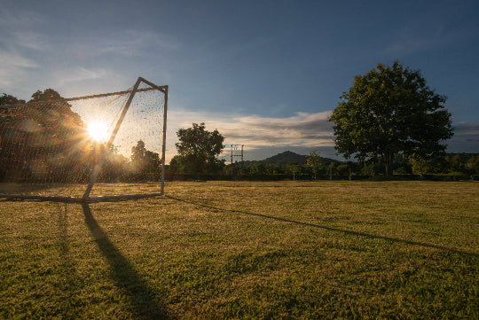Soccer goal on a grass field with sunset in the background