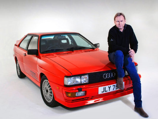 Man sitting on a red Audi car with a white background
