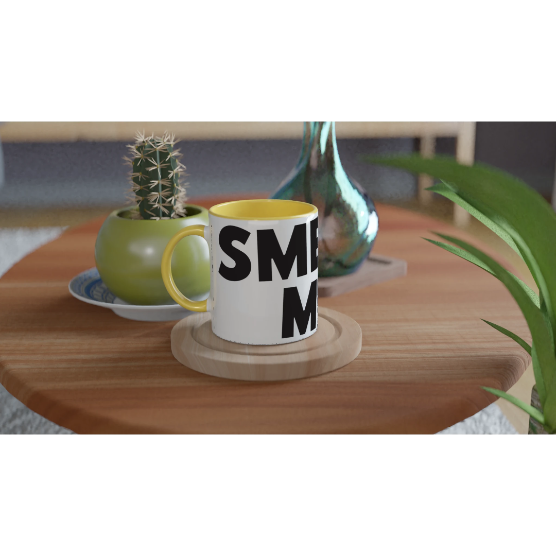 White mug with black text on a wooden table with a plant and decorative items.