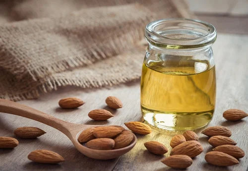 A jar of pure almond oil with some whole almonds.