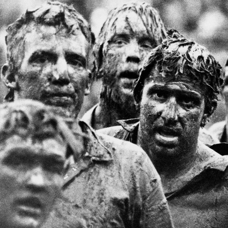 Black and white image of rugby players covered in mud