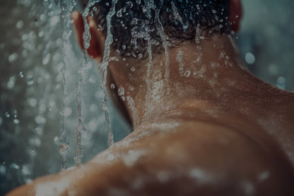 Person under a shower with water droplets on their skin