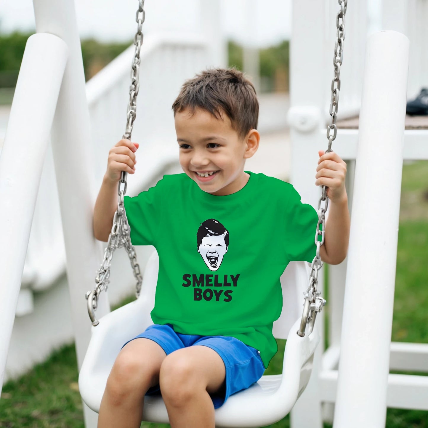 Child wearing a green t-shirt with 'SMELLY BOYS' text on a swing