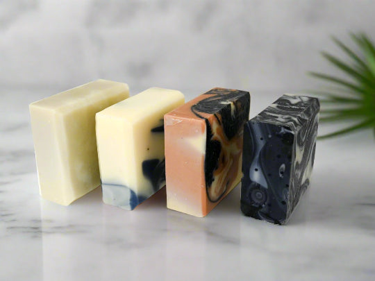 Four different bars of Smelly Men natural soap on a white surface with a neutral background