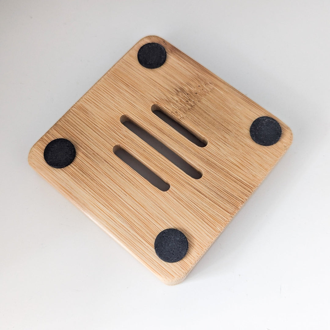 Wooden soap dish with four black suction cups on a white background