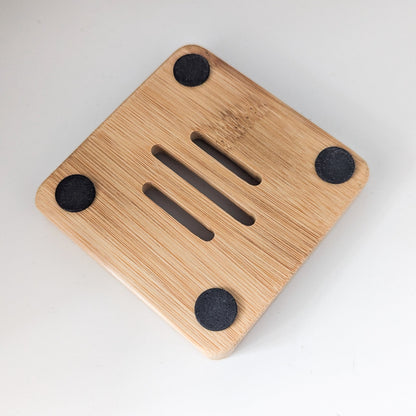 Wooden soap dish with four black suction cups on a white background