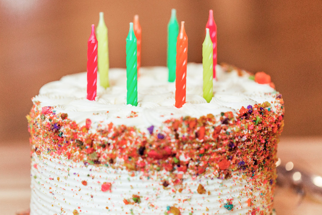 birthday cake with candles, white frosting and sprinkles.