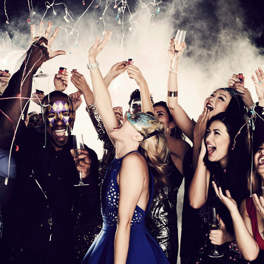 People celebrating with champagne glasses at a party, surrounded by confetti.