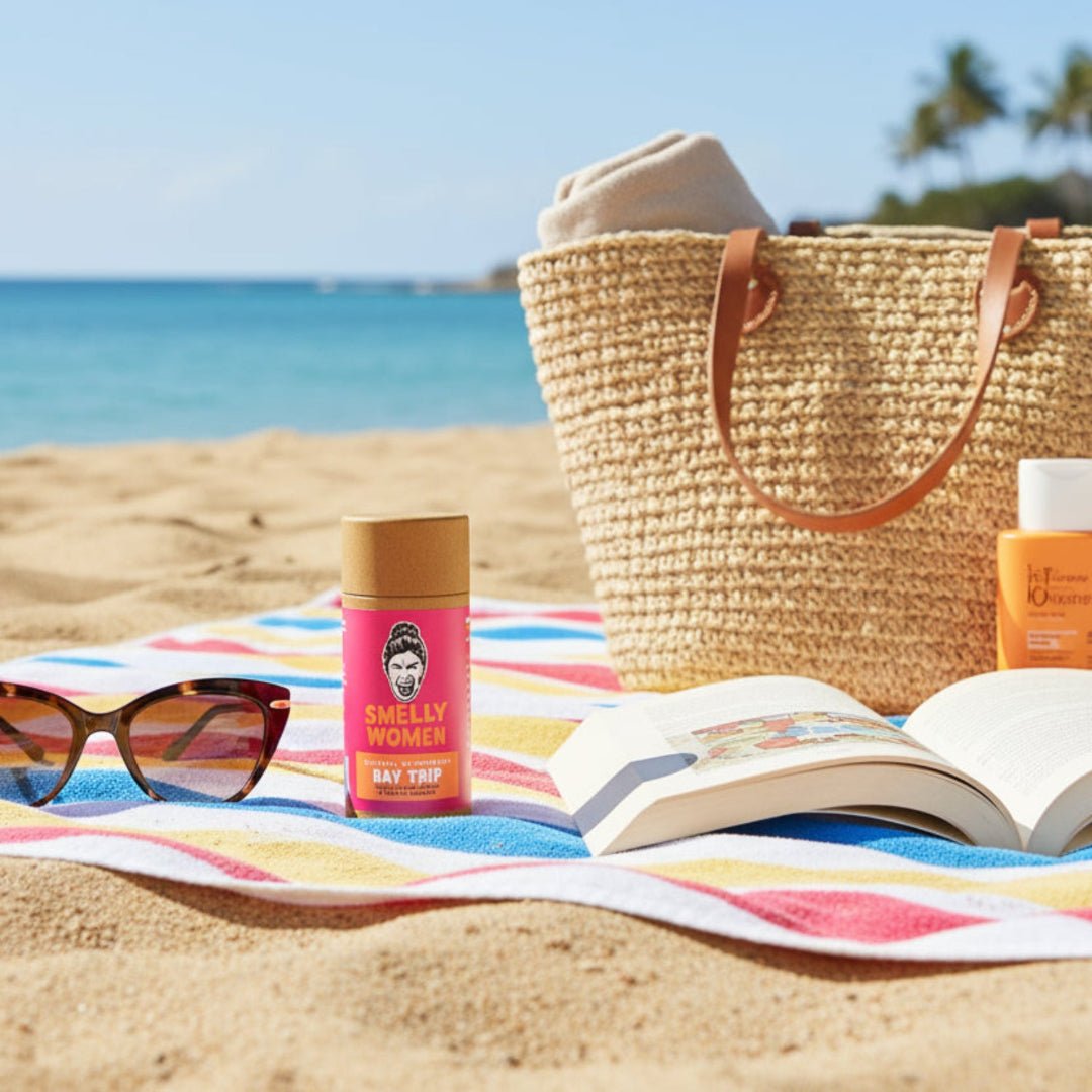 Beach scene with a straw bag, sunglasses, book, and 'Smelly Women' product.