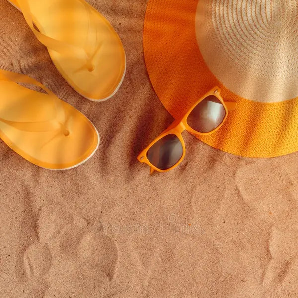 Yellow sandals, sunglasses, and straw hat on sand