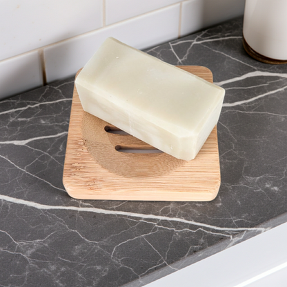 Bar of soap on a wooden soap dish on a marble countertop