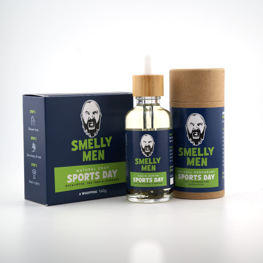 A bottle of Smelly Men Sports Day Shave Serum, a matching natural soap and a matching cardboard tube deodorant with a navy label, placed on a clean white background.